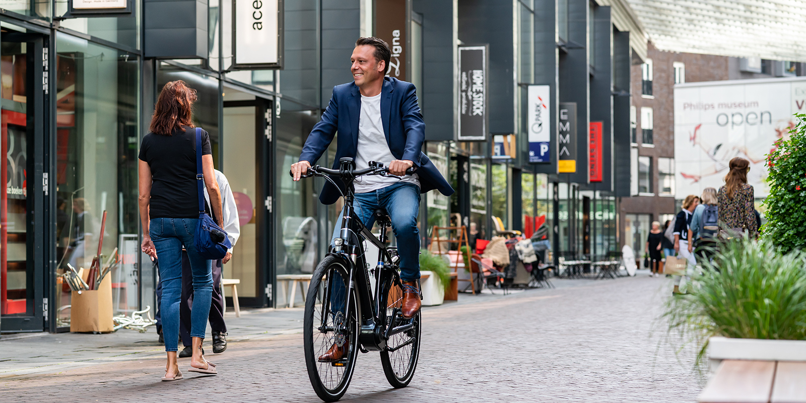 Man fiets op zijn elektrische fiets door een winkelstraat.